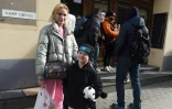 La réfugiée ukrainienne Katerina et son fils Ilia font la queue devant un cinéma où l'on distribue des vêtements et des jouets, le 11 avril 2022 à Lviv