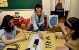 Le calligraphe Nguyen Thanh Tung (c) enseigne la calligraphie à des étudiants, chez lui à Hanoï, le 15 mai 2025 au Vietnam