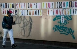Un passant devant un mur de l'hôpital Lariboisière à Paris, où figure le message "Macron sait qu'il peut compter sur les soignants. L'inverse?", le 12 mai 2020