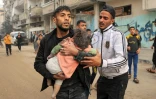 Un homme porte un enfant blessé lors d'un bombardement israélien, le 14 décembre 2023 à Rafah dans la bande de Gaza