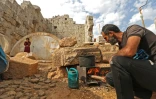 Un déplacé syrien entretient son feu de bois le 1er novembre 2020 dans le temple romain d'al-Baqirah, dans le nord-ouest de la Syrie, où il a installé sa famille