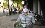 Une serveuse apporte un bol de soupe aux nouilles à un client dans une rue de Ho Chi Minh-Ville, le 8 septembre 2020 au Vietnam
