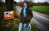Rosie Pearson, fondatrice d'un groupe d'action en Est-Anglie, à côté d'une pancarte contre l'installation de nouveaux pylônes électriques au bord d'une route à Ardleigh, dans l'est de l'Angleterre, le 27 janvier 2025