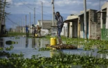 Des habitants se déplacent le 17 novembre 2025 à l'aide de radeaux de fortune dans une rue de ce qui fut leur quartier des rives du lac Naivasha, dans le centre du Kenya, inondé par la montée des eaux
