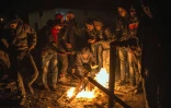 Migrants et réfugiés se réchauffent autour d'un feu de bois le 23 octobre 2015 à Gevgelija à la frontière entre la Macédoine et la Grèce