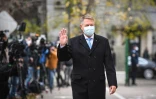 Le président roumain Klaus Iohannis salue à son arrivée au bureau de vote à Bucarest, le 6 décembre 2020