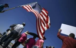 Des manifestants déploient le drapeau américain lors d'un rassemblement près d'un poste-frontière avec le Mexique, au Texas, pour protester contre les séparations de familles de migrants, le 21 juin 2018 