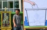 Un homme passe près d'un portrait du roi de Thaïlande Maha Vajiralongkorn et d'une affiche électorale à Bangkok, le 23 mars 2019