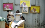 Un homme lit le journal "Catholic Mirror" devant des images du pape François à la basilique de la Sainte famille de Nairobi le 22 novembre 2015