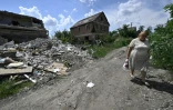 Une femme passe devant une habitation détruite dans le village ukrainien de Mala Rogan, proche de la frontière russe et théâtre de combats acharnés, le 28 juillet 2022
