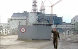 Un agent de sécurité de la centrale de Tchernobyl ordonne à un photographe d'arrêter de prendre des photos au portail d'accès au réacteur accidenté, le 2 décembre 1995