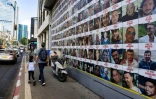 Des personnes passent devant des affiches des otages emmenés dans la bande de Gaza lors de l'attaque du Hamas le 7 octobre, à Tel-Aviv, le 11 août 2024