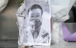 Une photo du médecin Li Wenliang, devant laquelle a été déposé un bouquet de fleurs, devant une aile de l'hôpital de Wuhan, en Chine, le 7 février 2020 