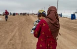 Une femme syrienne porte un enfant dans un camp pour déplacés, près de Hassaké, dans le nord-est de la Syrie en guerre, le 17 février 2020 