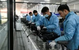 Des ouvriers travaillent sur une ligne de production de l'usine Neolix qui fabrique de petits véhicules utilitaires autonomes pour le transport de colis en ville, le 4 décembre 2025 à Yancheng dans la province chinoise du Jiangsu