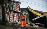 Un employé des chemins de fer passe devant les wagons endommagés d'un train de marchandises sur le pont du Grand Belt au Danemark après un accident meurtrier, le 2 janvir 2019