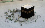 Des employés autour de la Kaaba, au sein de la Grande Mosquée à La Mecque, le 5 mars 2020, alors que le lieu a été évacué pour être désinfecté 