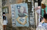 Une touriste se fait photographier près d'une fresque murale de l'ancien président taïwanais Tchang Kaï-chek, le 11 août 2022 aux îles de Kinmen, à Taïwan