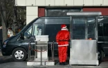Un agent de sécurité en costume de père Noël à l'entrée d'un parking le 24 décembre 2014 à Pékin 