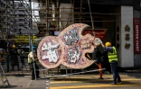 Des ouvriers travaillent avec l'ONG Tetra Neon Exchange démontent une enseigne lumineuse, le 13 mars 2023 à Hong Kong