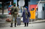 Un soldat slovaque porte la valise d'une Ukrainienne après avoir franchi la frontière à Vysne Nemecke, le 26 février 2022