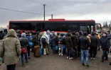 Des réfugiés de différents pays arrivés à pied en Pologne après avoir fui les combats en Ukraine, attendent de monter à bord d'un bus, le 27 février 2022 à Medyka