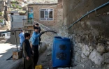 Des habitants remplissent des bidons d'eau potable à partir d'un camion-citerne sur les hauteurs de Kaboul, le 27 avril 2025 en Afghanistan