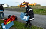 Des membres du SDIS débarquent d'un hélicoptère avec deux caisses contenant des vaccins contre le Covid-19 sur l'île de Hoëdic dans le Morbihan, le 29 janvier 2021
