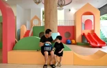 Un grand-père parle à son petit-fils près de jeux pour enfants, le 4 juin 2025 à Hanoï