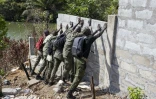 Des gardes-forestiers de l'Autorité nationale des aires protégées (NPAA) abattent le mur d'une maison en construction jugée illégale, située dans le parc national de la Péninsule de la Région Ouest, le 22 avril 2025 en Sierra Leone