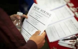"On embauche", un homme, photopgraphié en novembre, tient une fiche d'informations sur des offres d'emplois à New York.