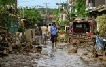 Une femme marche le long d'une rue couverte de boue après le passage du typhon Kalmaegi à Liloan, dans la province de Cebu aux Philippines, le 6 novembre 2025