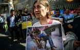 Une manifestante montre une photo de la guerre en Syrie lors d'un rassemblement à Istanbul destiné à protester contre les bombardements du régime syrien et de ses alliés sur Alep, le 1er octobre 2016