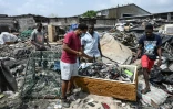 L'artiste ivoirien Mounou Désiré Koffi (C) cherche des claviers de téléphone usagés qu'il utilise pour réaliser des &oelig;uvres d'art à Koumassi, un quartier d'Abidjan, le 19 décembre 2021

