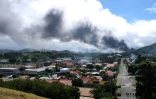 Un panache de fumée est visible au loin, alors que des émeutes ont lieu en Nouvelle-Calédonie en écho à une révision constitutionnelle examinée à l'Assemblée nationale, le 14 mai 2024 à Nouméa en Nouvelle-Calédonie