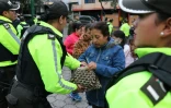 Un policier vérifie le sac à main d'une électrice dans un bureau de vote lors du second tour de l'élection présidentielle à Quito, le 13 avril 2025