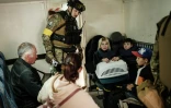 Policier contrôlant des familles dans une véhicule blindé avant leur évacuation de Lyssytchansk, dans l'est de l'Ukraine, le 15 mai 2022