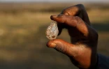 Un garçon tient ce qu'il pense être un diamant après la découverte de pierres non identifiées, dans le village sud-africain de KwaHlathi le 15 juin 2021