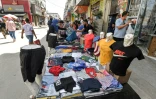 Une femme achète des vêtements à un marchand au souk de Bab el-Fellah, à Tunis, le 28 juillet 2021