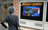 Une passante regarde un écran de télévision diffusant une alerte au tsunami à Tokyo, le 30 juillet 2025