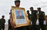 Un soldat thailandais porte le portrait de Saman Kunan, un ancien plonguer de la marine thaïlandaise mort lors d'une opération de ravitaillement des 12 enfants bloqués dans la grotte de Tham Luang, le 6 juillet 2018