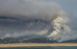 Plan aérien d'un incendie de forêt au nord du bassin d'Arcachon, dans le sud-ouest de la France, le 24 juillet 2026
This aerial photograph shows smoke emanating from the wildfire north of the Arcachon basin (seen Top) covering the forest, with a view of a beach and the Atlantic Ocean (bottom) near Lege-Cap-Ferret, southwestern France, on July 24, 2026. France has been battered by three heatwaves since May as part of increasingly common extreme weather episodes linked to climate change, causing excess deaths, drying up rivers and fuelling wildfires. Scientists have long warned that climate change caused by human use of fossil fuels will make periods of drought more intense and longer-lasting, creating the ideal conditions for wildfires.