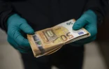 Un policier catalan examine une liasse de billets saisie pendant un raid contre une "ferme" illégale de cannabis dans la banlieue de Barcelone, le 6 octobre 2020