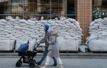 Un couple avec une poussette passe devant un magasin protégé par des sacs de sable à Dnipro, dans le centre de l'Ukraine, le 20 avril 2022