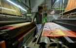 Tissage d'un sari sur un métier mécanique dans un atelier de Varanasi, le 20 novembre 2021 en Inde