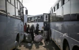 Un responsable sud-africain de l’immigration vérifie les noms de migrants en situation irrégulière faisant la queue pour monter dans des cars au Durban Drive-In, à Durban, le 29 juin 2026, en partance pour le Zimbabwe