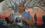 Sandra Gallegos tient un portrait de son fils disparu, Fernando Rosales, lors de l'inauguration d'une fresque murale en hommage aux personnes disparues, à l'Université d'El Salvador, à San Salvador, le 19 mars 2026