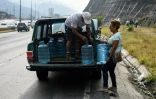 Des habitants du quartier Petare chargent des bidons d'eau dans une camionnette, le 1er avril 2019 à Caracas, au Venezuela