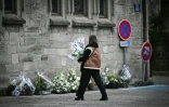 Une femme va déposer des fleurs devant la collégiale de Saint-Donat-sur-l'Herbasse, avant les obsèques de Thomas, un adolescent de 16 ans tué en marge d'un bal de village dans la Drôme, le 24 novembre 2023