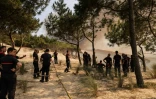 Des pompiers montent la garde dans une pinède alors que la fumée s'élève de la forêt à La Teste-de-Buch, devant la dune du Pilat, le 18 juillet 2022